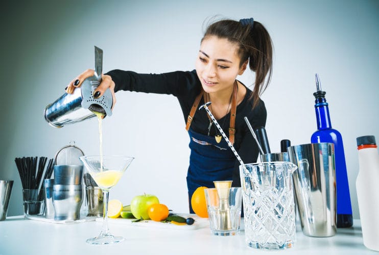 Friends making cocktails together at a house party